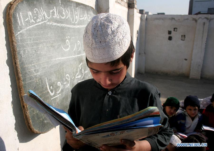 A boy reads a book during a class at a government school in northwest Pakistan's Peshawar, Dec. 11, 2014.