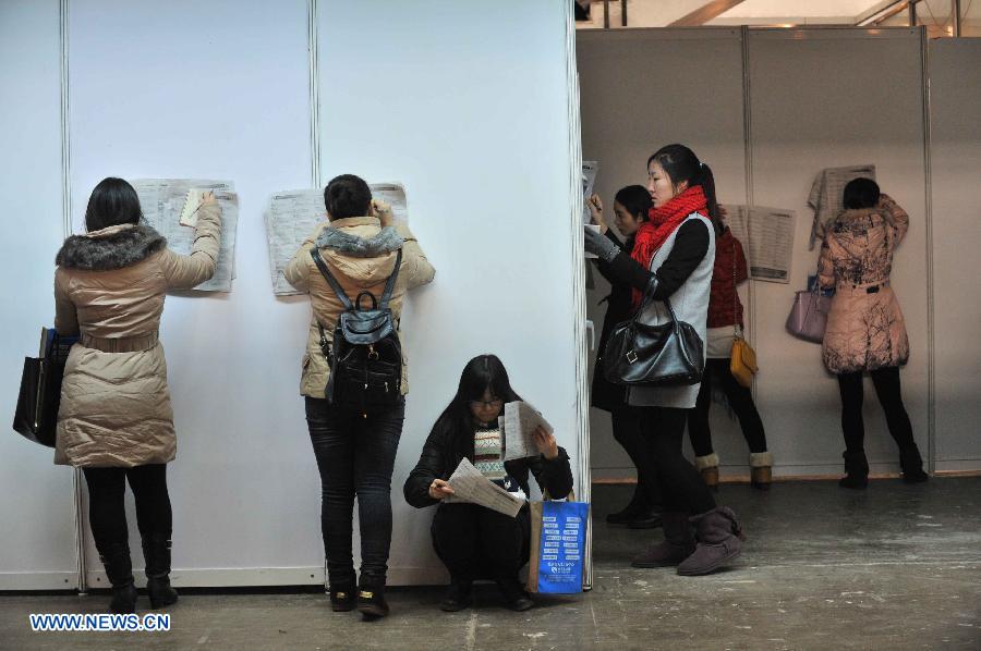 Job seekers look at employment information at a job fair for postgraduates in Beijing, capital of China, Dec. 18, 2014. About 18,000 opportunities were offered at the fair. (Xinhua/Li Wen)