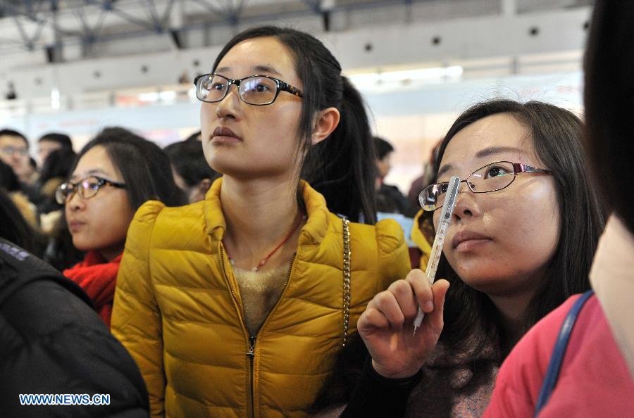 Job seekers look at employment information at a job fair for postgraduates in Beijing, capital of China, Dec. 18, 2014. About 18,000 opportunities were offered at the fair. (Xinhua/Li Wen)