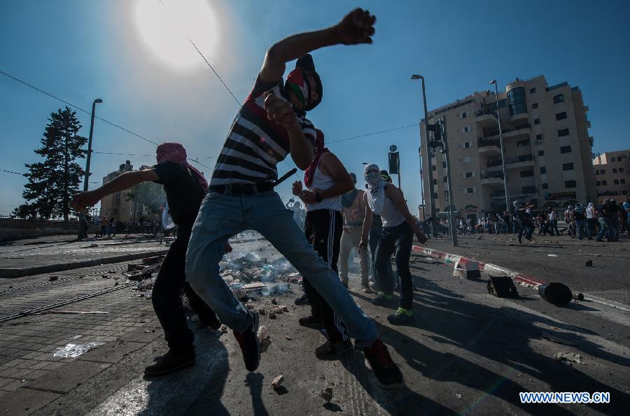 Palestinian demonstrators confront with Israeli policemen during clashes in Shuafat, an Arab neighborhood of northeastern Jerusalem, on July 4, 2014.