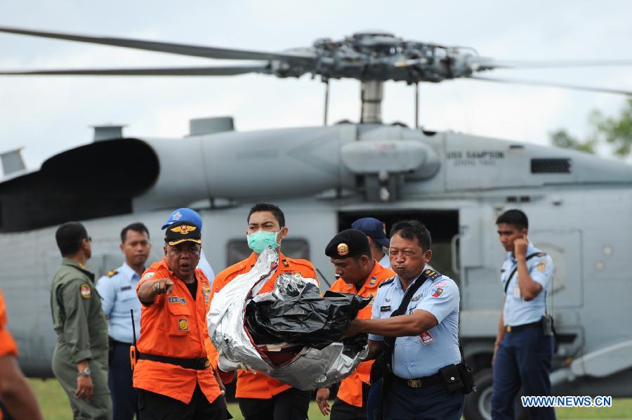 Search and Rescue (SAR) personnel and TNI officer carry the debris of AirAsia flight QZ8501 from a USS Navy helicopter at Iskandar Air Base, in Pangkalan Bun, Central Kalimantan, Indonesia, Jan. 2, 2015.