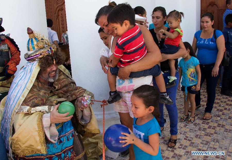 A person characterized as the Wise Man Caspar gives presents to children during a pilgrimage for the celebration of Jan. 6, the Day of the Three Wise Men, in Suchitoto city, El Salvador, on Jan 4, 2015.