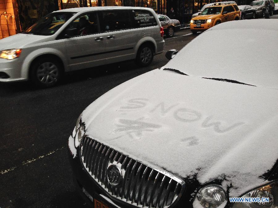 A vehicle goes past another one covered in snow during a snowfall in New York, the United States, Jan. 6, 2015.