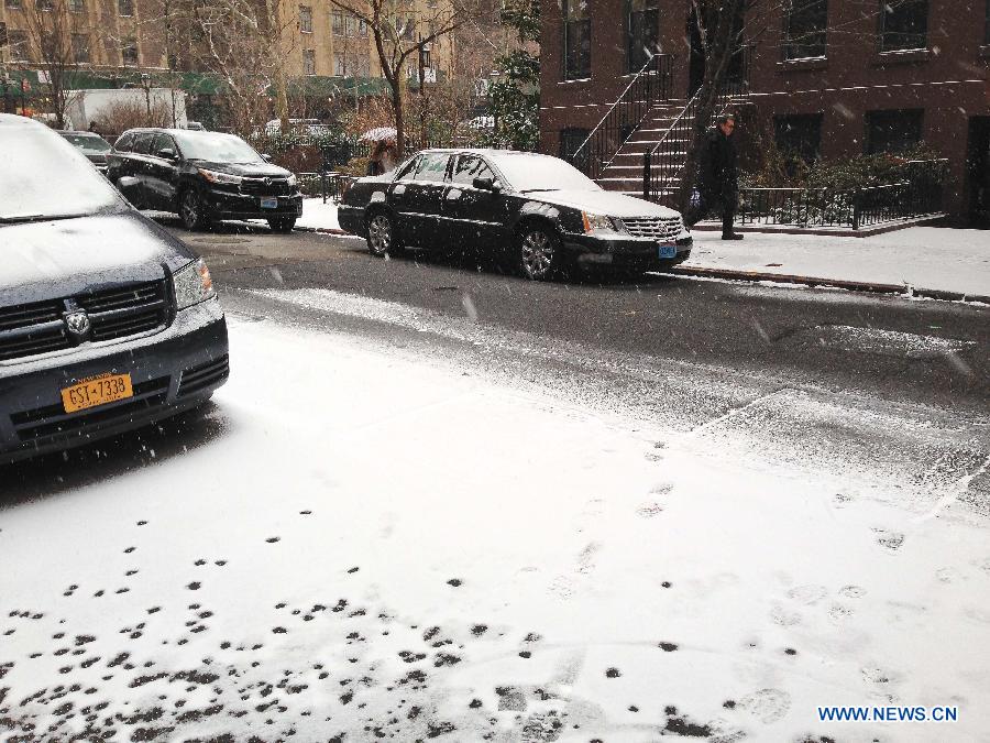 Pedestrians walk along the sidewalk during a snowfall in New York, the United States, Jan. 6, 2015.