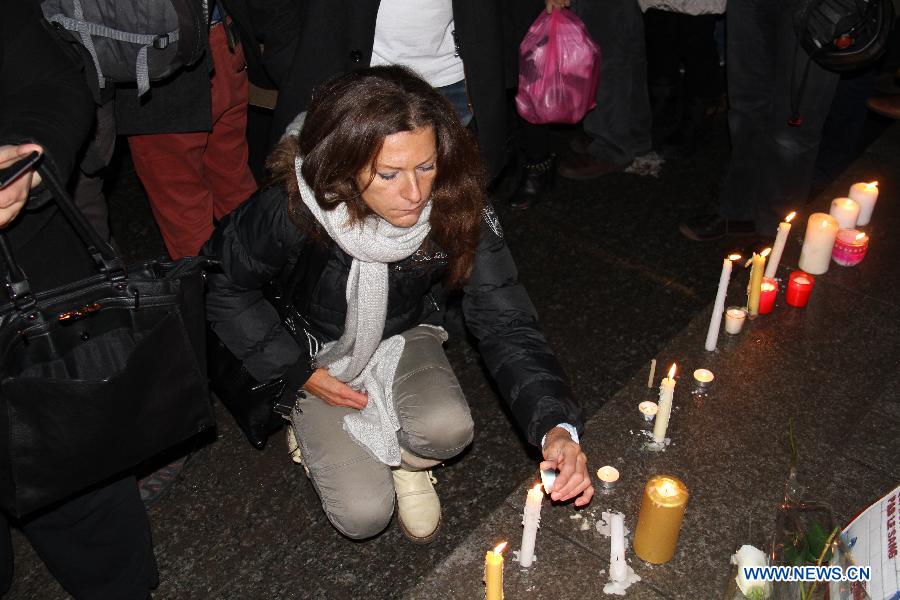 A woman lights up a candle during a rally to protest against the deadly Paris shooting incident in Strasbourg, France, on Jan. 7, 2015. 