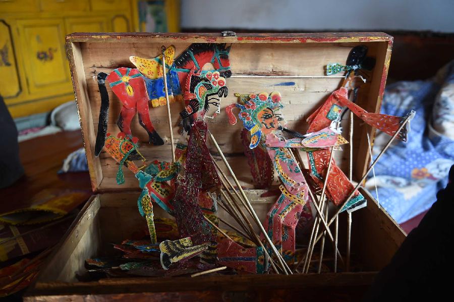 Leather puppets that belong to shadow play puppeteer Cao Zhiqin are seen in a wooden box that carries them in Zhenhu Township of Xiji County, Guyuan, northwest China's Ningxia Hui Autonomous Region, Jan. 12, 2014. The Chinese shadow play is performed by manipulating flat leather puppets against a lit-up translucent screen. The art form was registered in the Representative List of the Intangible Cultural Heritage of Humanity by the UNESCO in 2011. Cao Zhiqin, who is 67, started learning shadow puppetry when he was a child. As head of a local puppetry troupe, Cao has worked hard to promote shadow puppetry, hoping that people can still enjoy the fun of this folk art. (Xinhua/Li Ran)