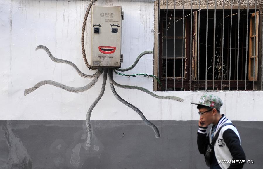 A man walks past a cartoon mural which takes advantage of an electricity meter case in a residential community of Changsha, capital of central China's Hunan Province, Jan. 15, 2015. The exterior walls of a residential community in Changsha have been rejuvenated, after a group of young cartoonists were invited to create some 40 cartoon murals on them. The mural painters not only drew on plain walls, but also blended their work with the environment by integrating objects on the scene (newspaper boxes, electricity meter cases, air-conditioning units, etc.) into the murals. (Xinhua/Li Ga)