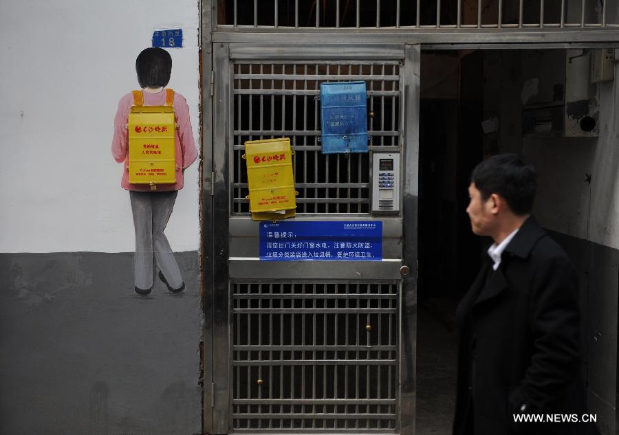 A man looks at a cartoon wall painting which takes advantage of a newspaper box in a residential community of Changsha, capital of central China's Hunan Province, Jan. 15, 2015. The exterior walls of a residential community in Changsha have been rejuvenated, after a group of young cartoonists were invited to create some 40 cartoon murals on them. The mural painters not only drew on plain walls, but also blended their work with the environment by integrating objects on the scene (newspaper boxes, electricity meter cases, air-conditioning units, etc.) into the murals. (Xinhua/Li Ga)
