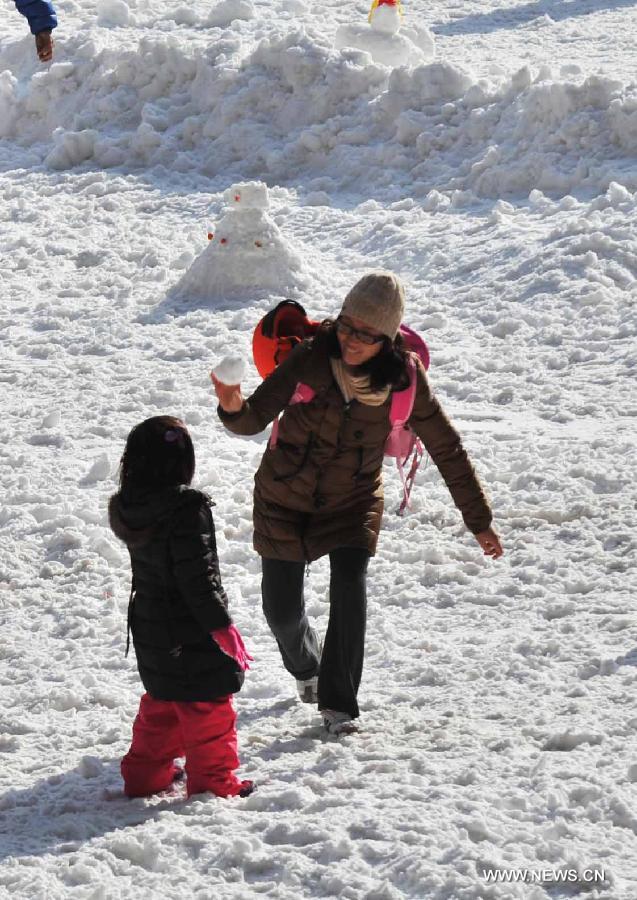 A parent and her daughter enjoy their weekend leisure time in a seasonal snow park at the National Stadium, or the Bird's Nest, in Beijing, capital of China, Jan. 17, 2015.