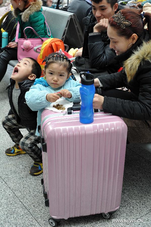 Ma Wenqiang (1st L), Ma Junli (2nd L) and their parents wait for their train home at the railway station of Yinchuan, capital of northwest China's Ningxia Hui Autonomous Region, Feb. 2, 2015. 