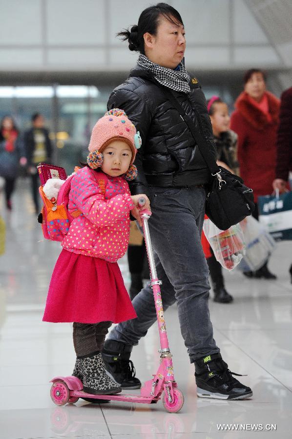 A little girl riding a scooter heads for her train home with her mother at the railway station of Yinchuan, capital of northwest China's Ningxia Hui Autonomous Region, Feb. 2, 2015. 