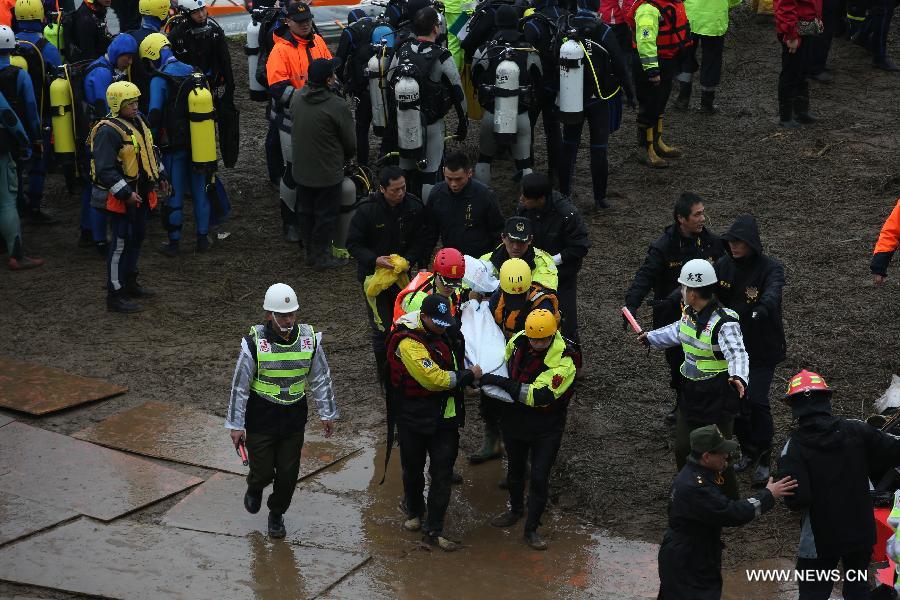 Rescuers transfer the body of a plane crash victim on the bank of Keelung River in Taipei, southeast China's Taiwan, Feb. 6, 2015. 