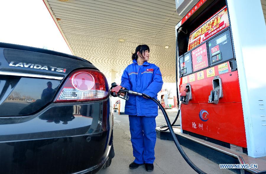 A worker fills up a car with fuel at a gas station in Cangzhou, north China's Hebei Province, Feb. 9, 2015.