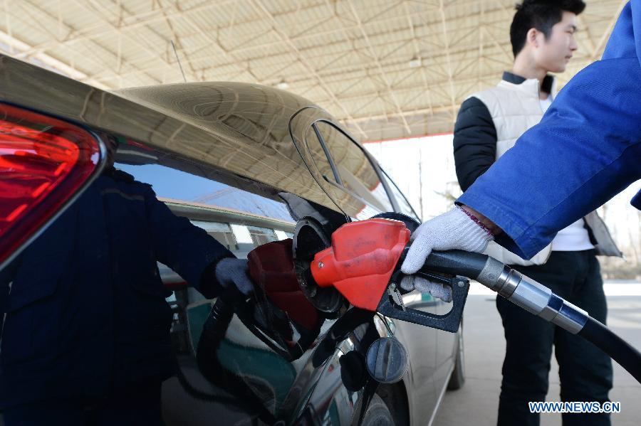 A worker fills up a car with fuel at a gas station in Baoding, north China's Hebei Province, Feb. 9, 2015. 