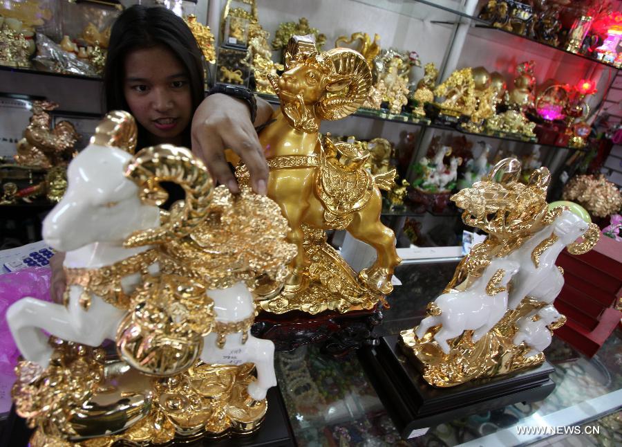 A saleslady wipes the golden sheep displayed inside a lucky charms shop in preparation for the Chinese Lunar New Year celebrations in Manila, the Philippines on Feb. 10, 2015.