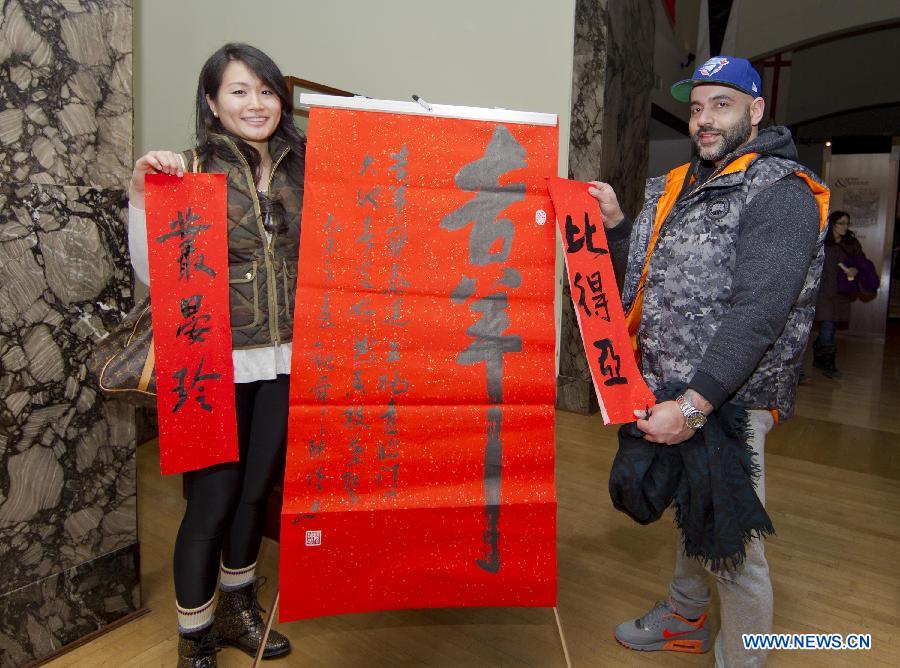 Two visitors pose for photos with their Chinese names in Chinese calligraphy during the 2015 Chinese New Year Extravaganza at the Royal Ontario Museum in Toronto, Canada, Feb. 14, 2015.