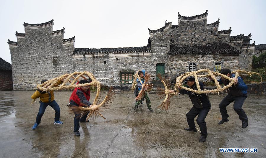 Villager Wang Xiaoqing (2nd R) teaches young people perform bullfight dance called 'Huoxianniu' (fire fairy cattle) with straw bundles in Zhengyuan Village of Qidu Township in Chenzhou City, central China's Hunan Province, March 3, 2015. Local villagers, who has a tradition to worship farm cattle, followed the custom to tie red flowers on cattle and perform bullfight dance with straw bundles which are inserted with litten incenses on the 13th day of the first month of the lunar year. (Xinhua/Li Ga) 