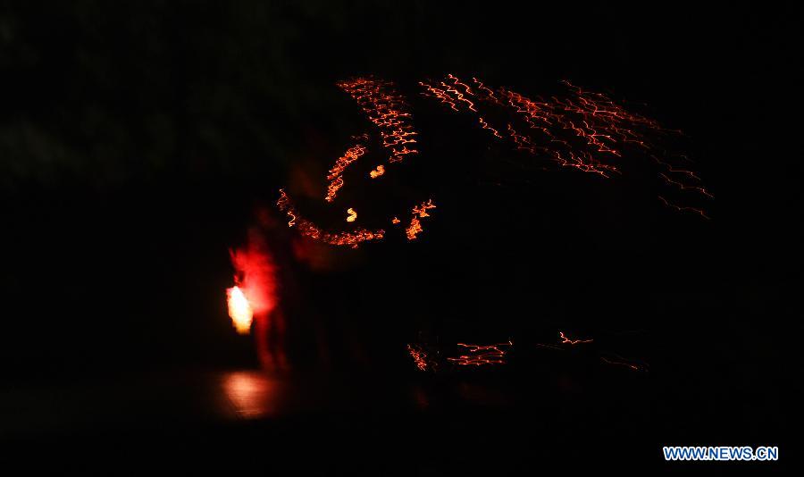 Villagers perform bullfight dance called 'Huoxianniu' (fire fairy cattle) with incense-inserted straw bundles in Zhengyuan Village of Qidu Township in Chenzhou City, central China's Hunan Province, March 3, 2015. Local villagers, who has a tradition to worship farm cattle, followed the custom to tie red flowers on cattle and perform bullfight dance with straw bundles which are inserted with litten incenses on the 13th day of the first month of the lunar year. (Xinhua/Li Ga) 