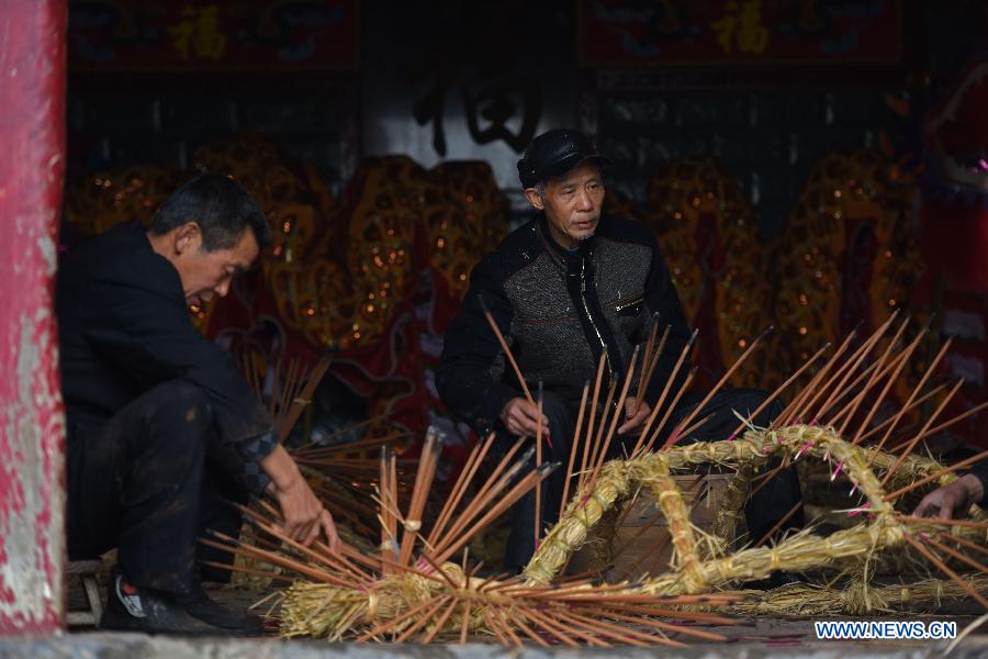 Villager Wang Xiaoqing (R) and former village secretary Wang Ziwu insert incenses on straw bundles to perform a bullfight dance called 'Huoxianniu' (fire fairy cattle) in Zhengyuan Village of Qidu Township in Chenzhou City, central China's Hunan Province, March 3, 2015. Local villagers, who has a tradition to worship farm cattle, followed the custom to tie red flowers on cattle and perform bullfight dance with straw bundles which are inserted with litten incenses on the 13th day of the first month of the lunar year. (Xinhua/Li Ga) 