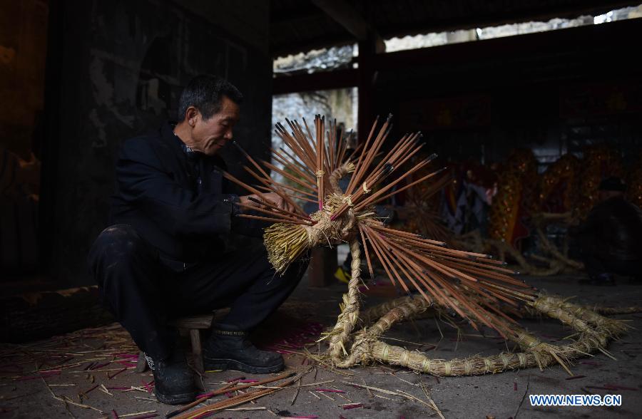 Former village secretary Wang Ziwu inserted incenses on straw bundles for the bullfight dance 'Huoxianniu' (fire fairy cattle) in Zhengyuan Village of Qidu Township in Chenzhou City, central China's Hunan Province, March 3, 2015. Local villagers, who has a tradition to worship farm cattle, followed the custom to tie red flowers on cattle and perform bullfight dance with straw bundles which are inserted with litten incenses on the 13th day of the first month of the lunar year. (Xinhua/Li Ga) 