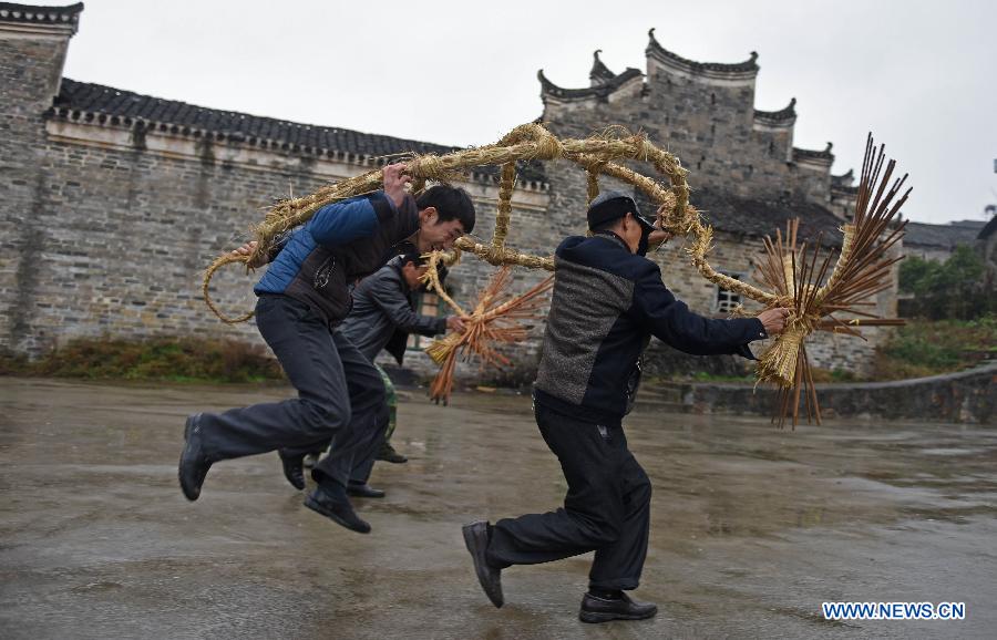 Villager Wang Xiaoqing (1st R) teaches young people perform bullfight dance called 'Huoxianniu' (fire fairy cattle) with straw bundles in Zhengyuan Village of Qidu Township in Chenzhou City, central China's Hunan Province, March 3, 2015. Local villagers, who has a tradition to worship farm cattle, followed the custom to tie red flowers on cattle and perform bullfight dance with straw bundles which are inserted with litten incenses on the 13th day of the first month of the lunar year. (Xinhua/Li Ga) 