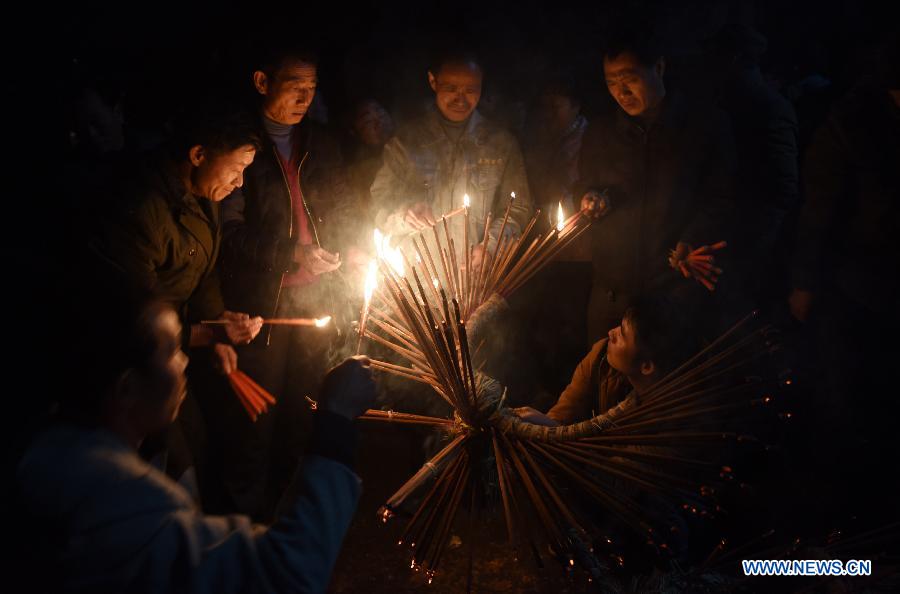 Villagers light incenses inserted on straw bundles for performing bullfight dance called 'Huoxianniu' (fire fairy cattle) in Zhengyuan Village of Qidu Township in Chenzhou City, central China's Hunan Province, March 3, 2015. Local villagers, who has a tradition to worship farm cattle, followed the custom to tie red flowers on cattle and perform bullfight dance with straw bundles which are inserted with litten incenses on the 13th day of the first month of the lunar year. (Xinhua/Li Ga) 