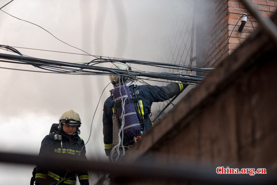 Firefighters pump water into a blazing building in a residential area in downtown Beijing on Thursday, March 5, the traditional Chinese Lantern Festival. The building located between Linglong Rd. and Qixiancun Rd. in Haidian District, is used as a warehouse of Gehua, Beijing's local cable TV service provider. The burning rubber from the cable wire gives out a strong black smoke. [Photo by Chen Boyuan / China.org.cn]