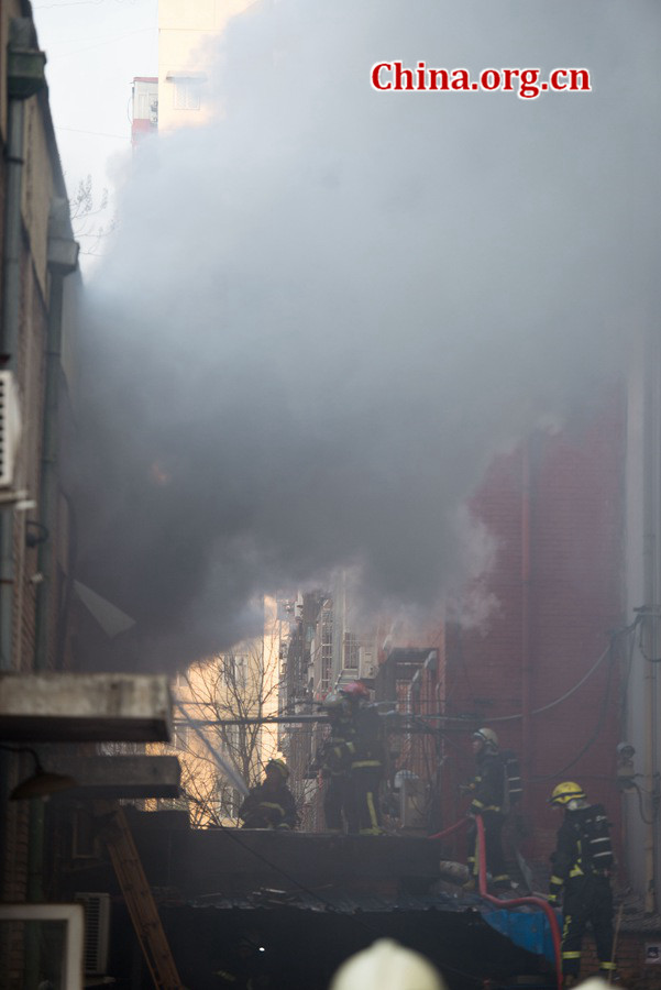 Firefighters pump water into a blazing building in a residential area in downtown Beijing on Thursday, March 5, the traditional Chinese Lantern Festival. The building located between Linglong Rd. and Qixiancun Rd. in Haidian District, is used as a warehouse of Gehua, Beijing's local cable TV service provider. The burning rubber from the cable wire gives out a strong black smoke. [Photo by Chen Boyuan / China.org.cn]