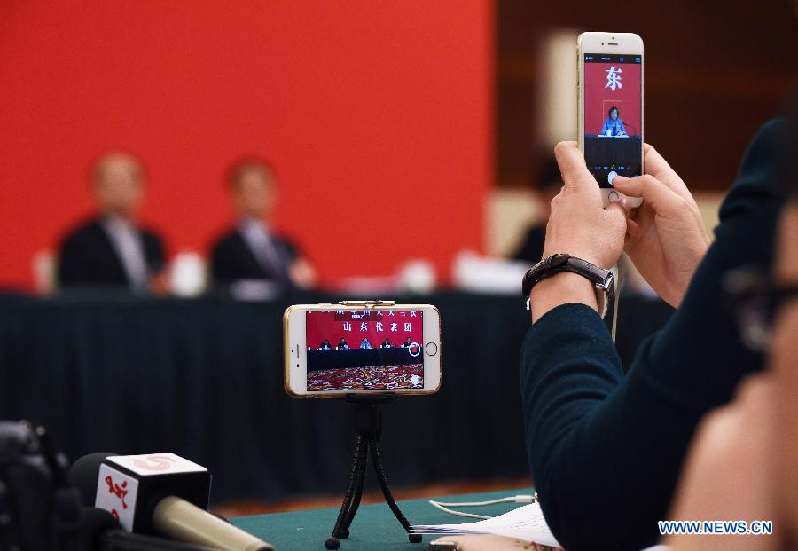 A journalist uses a cellphone and a mini tripod to shoot videos during a a panel discussion of deputies to China's 12th National People's Congress (NPC) from east China's Shandong Province in Beijing, capital of China, March 7, 2015. (Xinhua/Wang Jianhua)  