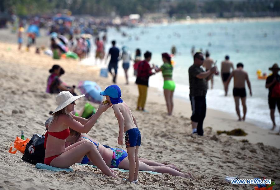 Tourists play on a beach in Sanya, a resort city in south China's Hainan Province, March 8, 2015. 