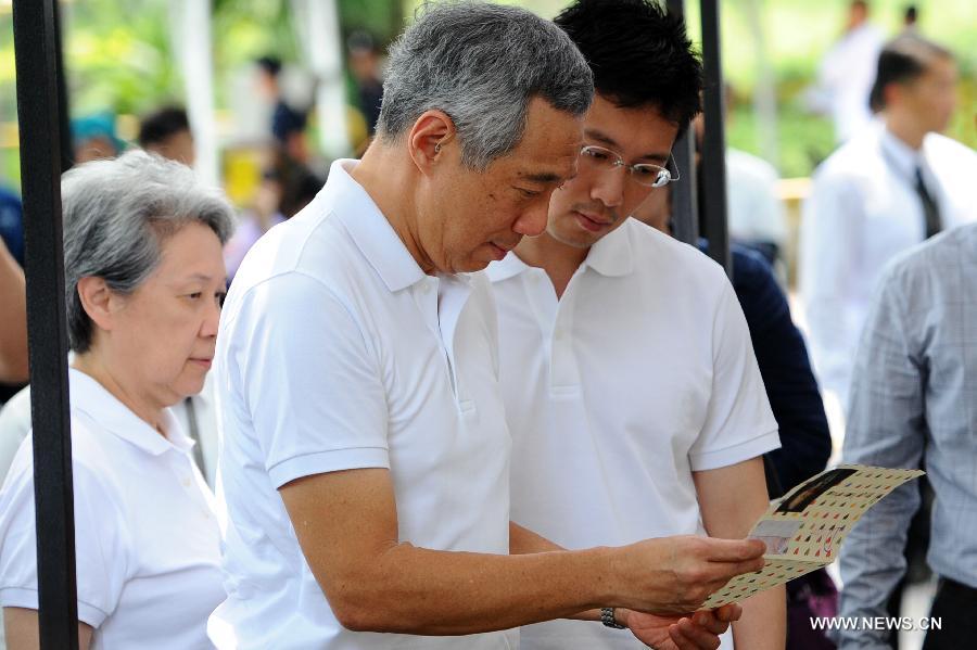 Singapore's Prime Minister Lee Hsien Loong (C) accompanied by his wife Ho Ching (L) views a condolence card at the Istana tribute site for Singapore's former prime minister Lee Kuan Yew in Singapore, March 24, 2015. Singapore's Prime Minister Lee Hsien Loong spoke to visitors at the Istana Gate on Tuesday when he stopped to read some of the messages left for Singapore's founding prime minister Lee Kuan Yew. (Xinhua/Then Chih Wey)