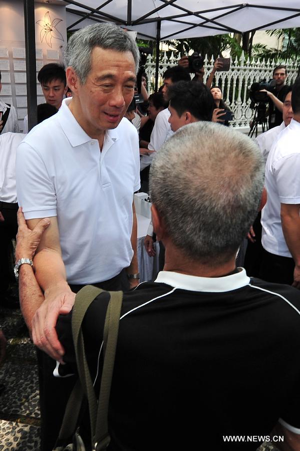 Singapore's Prime Minister Lee Hsien Loong (L) speaks with a Singaporean at the Istana tribute site for Singapore's former prime minister Lee Kuan Yew in Singapore, March 24, 2015. Singapore's Prime Minister Lee Hsien Loong spoke to visitors at the Istana Gate on Tuesday when he stopped to read some of the messages left for Singapore's founding prime minister Lee Kuan Yew. (Xinhua/Then Chih Wey)