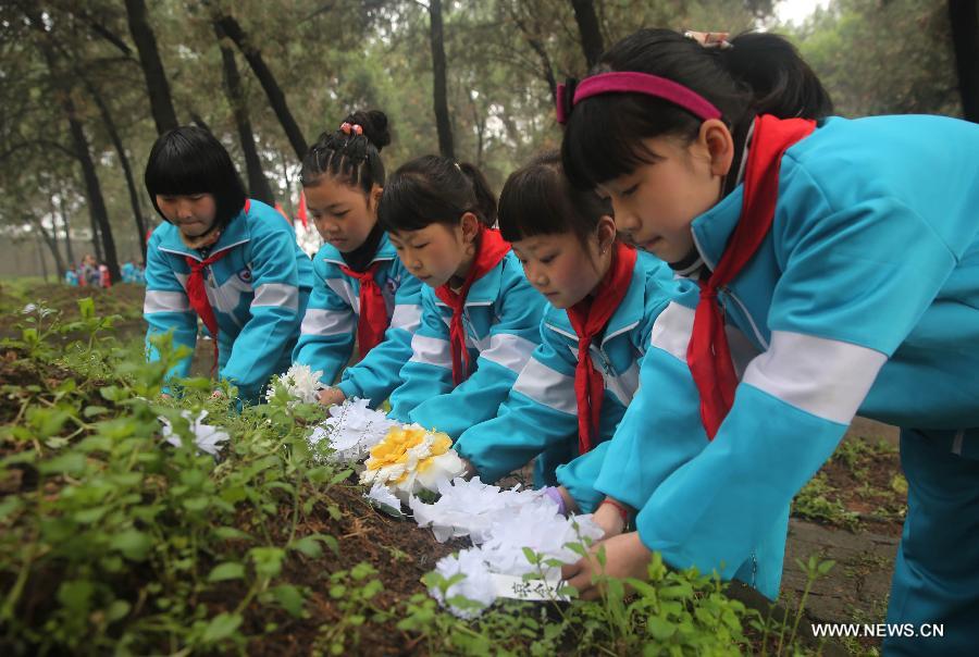 Pupils lay paper flowers to a tomb at a Martyrs' Park in Pingdingshan, central China's Henan Province, April 3, 2015. People started mourning for departed relatives and martyrs as the Qingming Festival is coming. (Xinhua/He Wuchang)