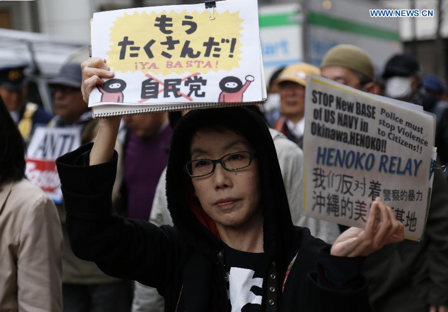 A woman holds a placard during a demonstration to protest against the revision of the pacifist Article 9 of the Japanese Constitution in Tokyo, Japan, April 11, 2015.