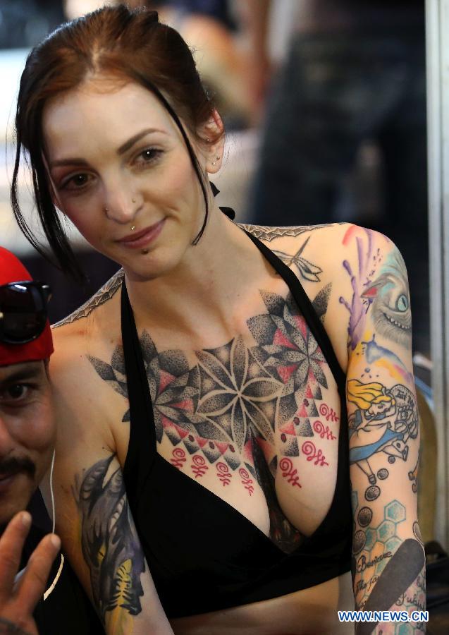 A tattoo girl poses for photos with a visitor during the 5th International Nepal Tattoo Convention in Kathmandu, Nepal, April 24, 2015. 