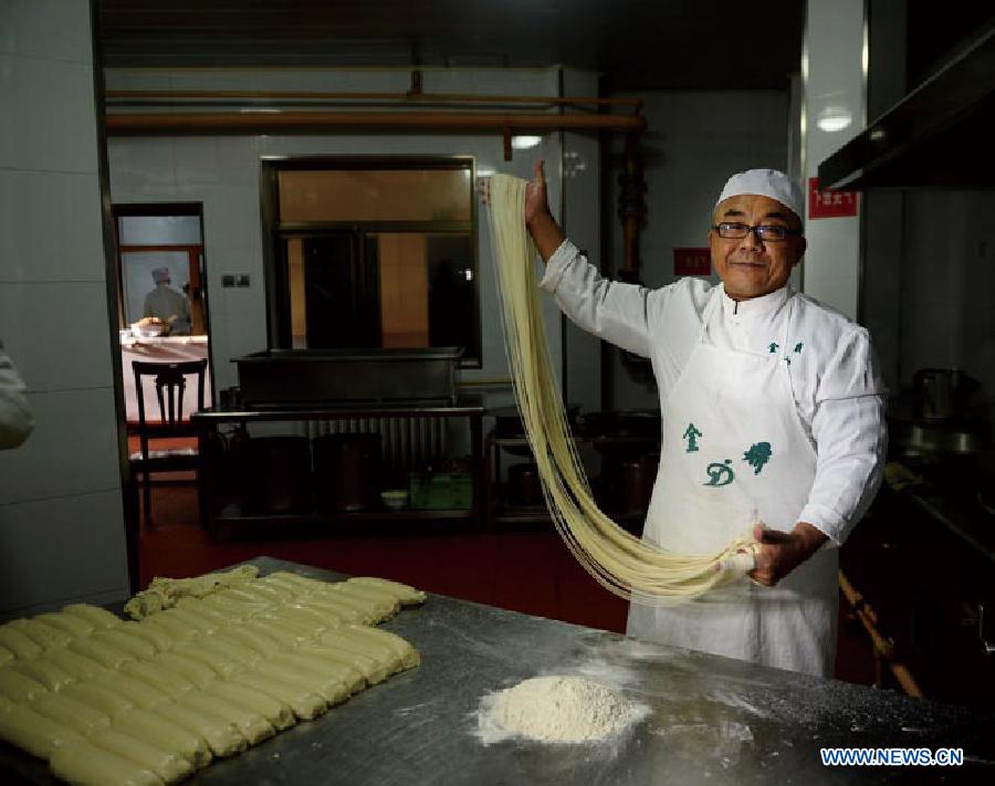 Ma Wenbin, an inheritor of Lanzhou beef lamian, tries to pull noodles at a noodle shop in Lanzhou, capital of northwest China's Guansu Province, Jan. 22, 2014. 