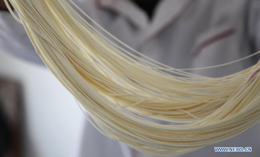 A cook pulls noodles at a noodle shop in Lanzhou, capital of northwest China's Guansu Province, Jan. 22, 2014.