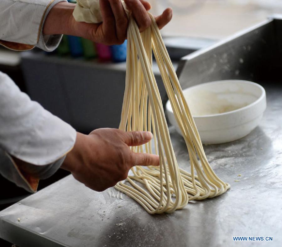 A cook pulls noodles at a noodle shop in Lanzhou, capital of northwest China's Guansu Province, Jan. 22, 2014. 