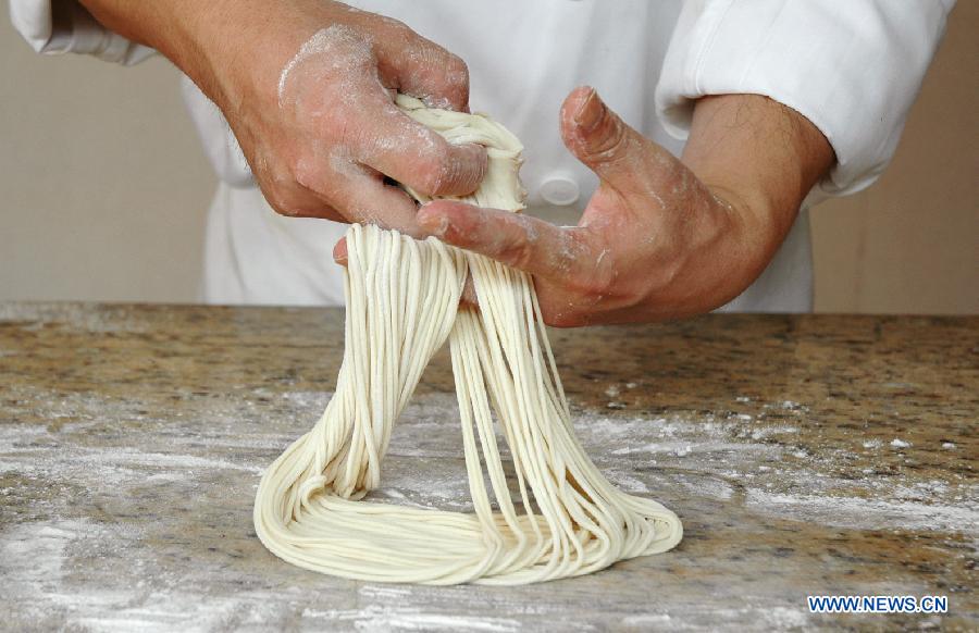 A cook tries to pull noodles at a noodle shop in Lanzhou, capital of northwest China's Guansu Province, Jan. 22, 2014.