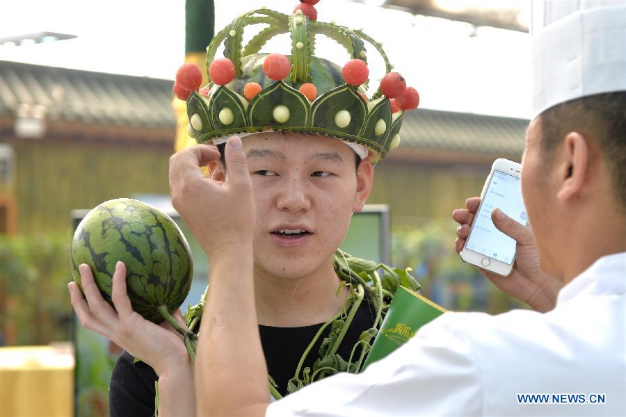 A chef puts his watermelon carving on a man's head during the 27th Daxing Watermelon Festival in Panggezhuang Township of Daxing District of Beijing, capital of China, May 25, 2015. (Xinhua/Gao Jianjun) 