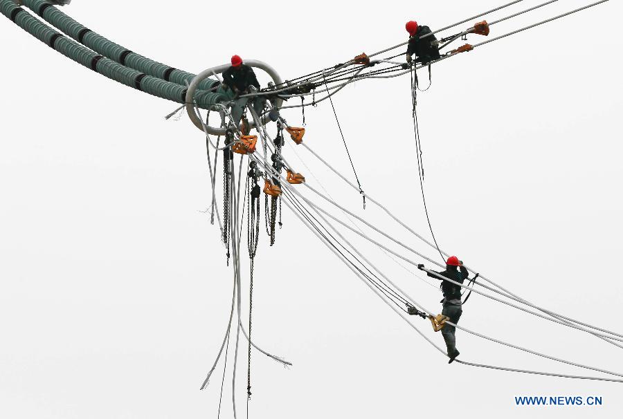 Workers work on 1,000-kilovolt power transmission project about a hundred meters above the ground in Wangdian Township of Huai'an City, east China's Jiangsu Province, May 30, 2015. 
