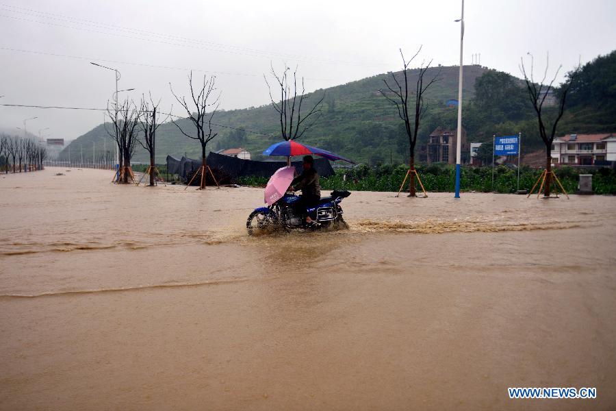 A villager rides on a road submerged by flood water in Tianba Village, Yuqing County, Zunyi City of southwest China's Guizhou Province, June 10, 2015.