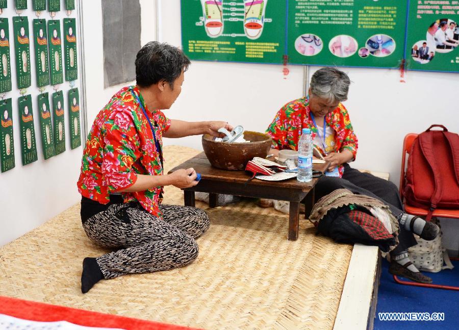 Exhibitors show the creation of traditional shoes during an intangible cultural heritages show in Harbin, capital of northeast China's Heilongjiang Province, June 11, 2015. 