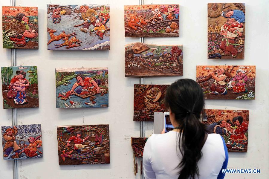 A visitor looks at the carved wood painting during an intangible cultural heritages show in Harbin, capital of northeast China's Heilongjiang Province, June 11, 2015.