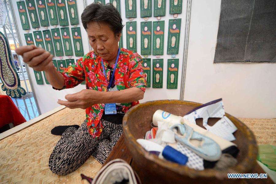 A exhibitor shows the creation of traditional shoes during an intangible cultural heritages show in Harbin, capital of northeast China's Heilongjiang Province, June 11, 2015.