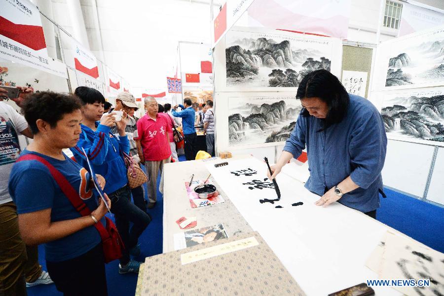 Vice-dean of the Artistic College of China Mo Tao (R) shows the Chinese calligraphy during an intangible cultural heritages show in Harbin, capital of northeast China's Heilongjiang Province, June 11, 2015. 