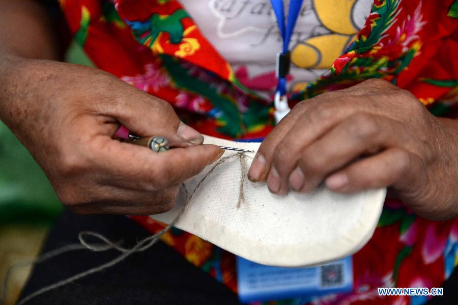 A exhibitor shows the creation of traditional shoes during an intangible cultural heritages show in Harbin, capital of northeast China's Heilongjiang Province, June 11, 2015. 