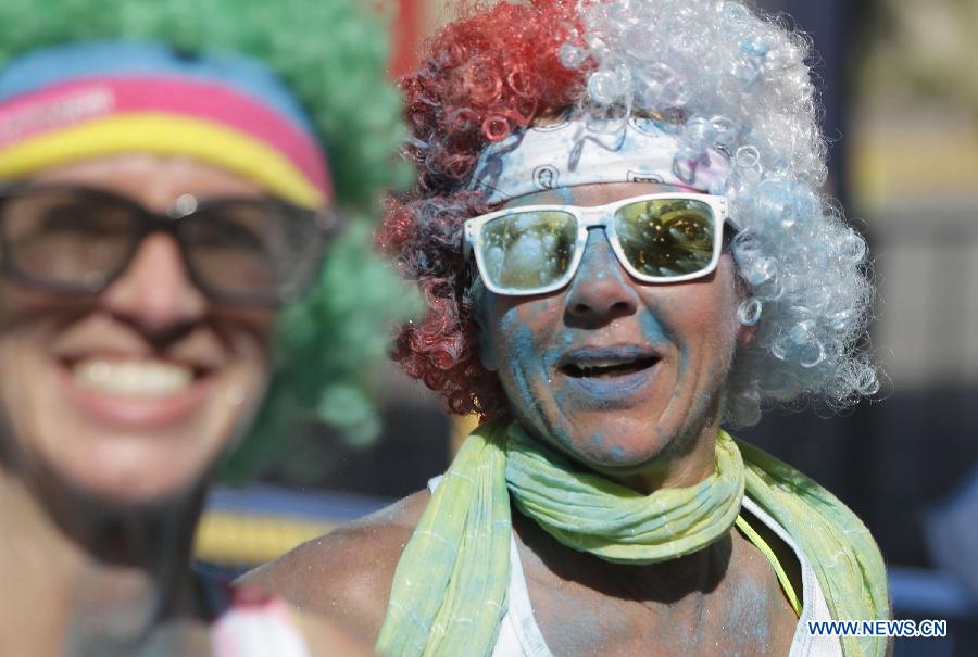 Runners covered with colour powder smile during the colour run held in Vancouver, Canada, June 13, 2015. 