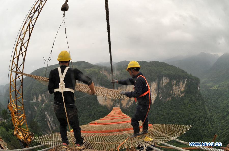 Workers build the vitreous bridge above the grand canyon in Zhangjiajie, central China's Hunan Province, June 15, 2015.