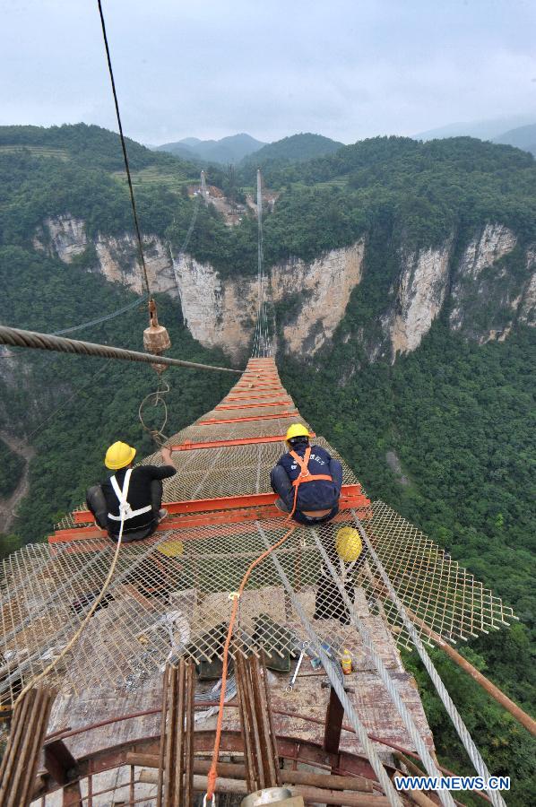 Workers build the vitreous bridge above the grand canyon in Zhangjiajie, central China's Hunan Province, June 15, 2015.